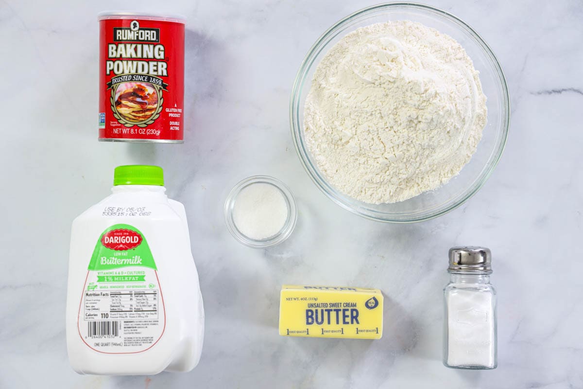 Overhead image of ingredients for homemade buttermilk biscuits on a marble background.